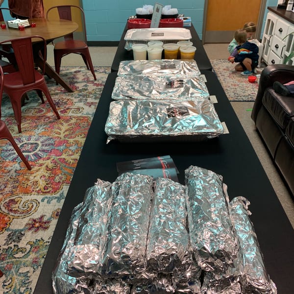 Catering spread from Campione's Taste of Chicago with foil-wrapped trays, cups of sauces, and brochures.